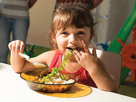 Niña comiendo comida ecológica en el comedor del colegio