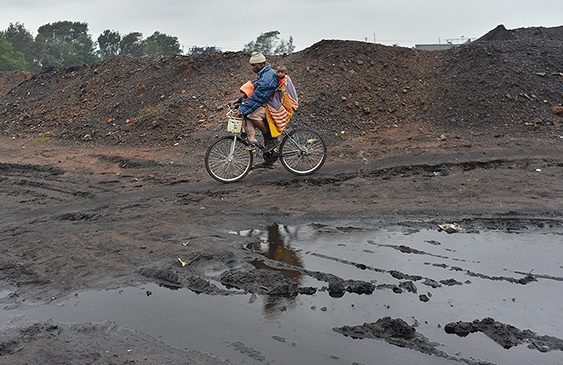 Hombre con sus hijos sobre una bicicleta cruzando tierras contaminadas