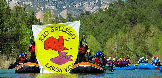 Gente en barca por el río Biscarrues con una pancarta de victoria