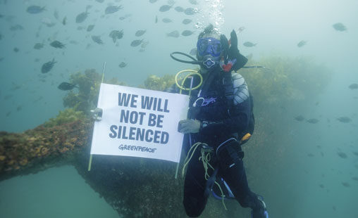Inmersión en el pecio del Rainbow Warrior en Matauri Bay, Nueva Zelanda Dos buceadores de Greenpeace sostienen un cartel en el que se lee «No nos silenciarán».