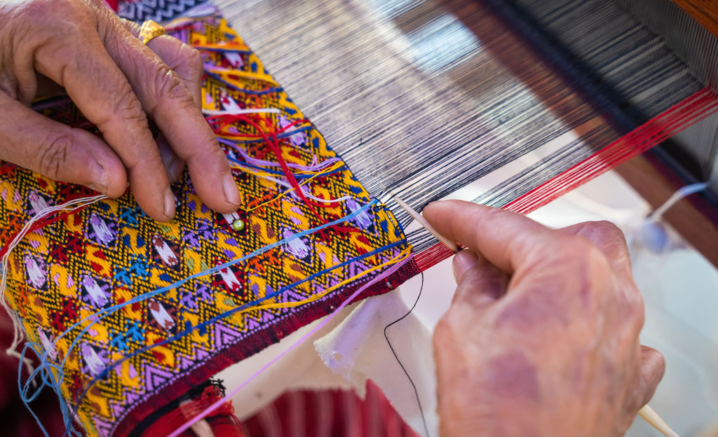 Mujer tejiendo a mano telas tradicionales y técnicas textiles locales con una artesanía única