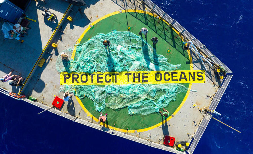 Vista aérea de la cubierta del Arctic Sunrise con una «red fantasma» recuperada del mar de los Sargazos y una pancarta con el lema «Protege los océanos».