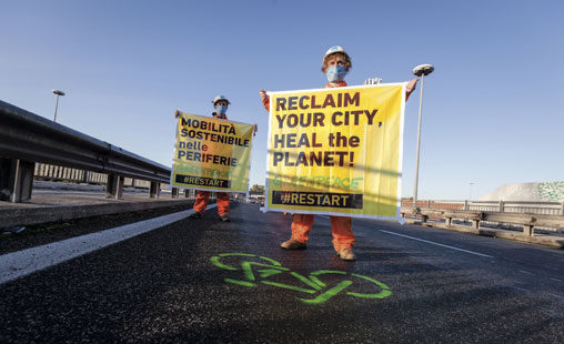 Activistas de Greenpeace Italia transforman una concurrida carretera de Roma en un carril bici para todos y sostienen en las manos una pancarta que dice: Recupera tu ciudad, salva el planeta.