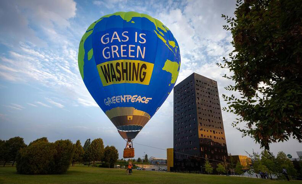 Un globo gigante con el mensaje «El gas es green... whasing» con la forma del planeta Tierra sobrevuela la zona de aparcamiento reservada para los delegados de Gastech, la reunión más importante del mundo de empresas de gas, GNL e hidrógeno, que asisten a la feria.